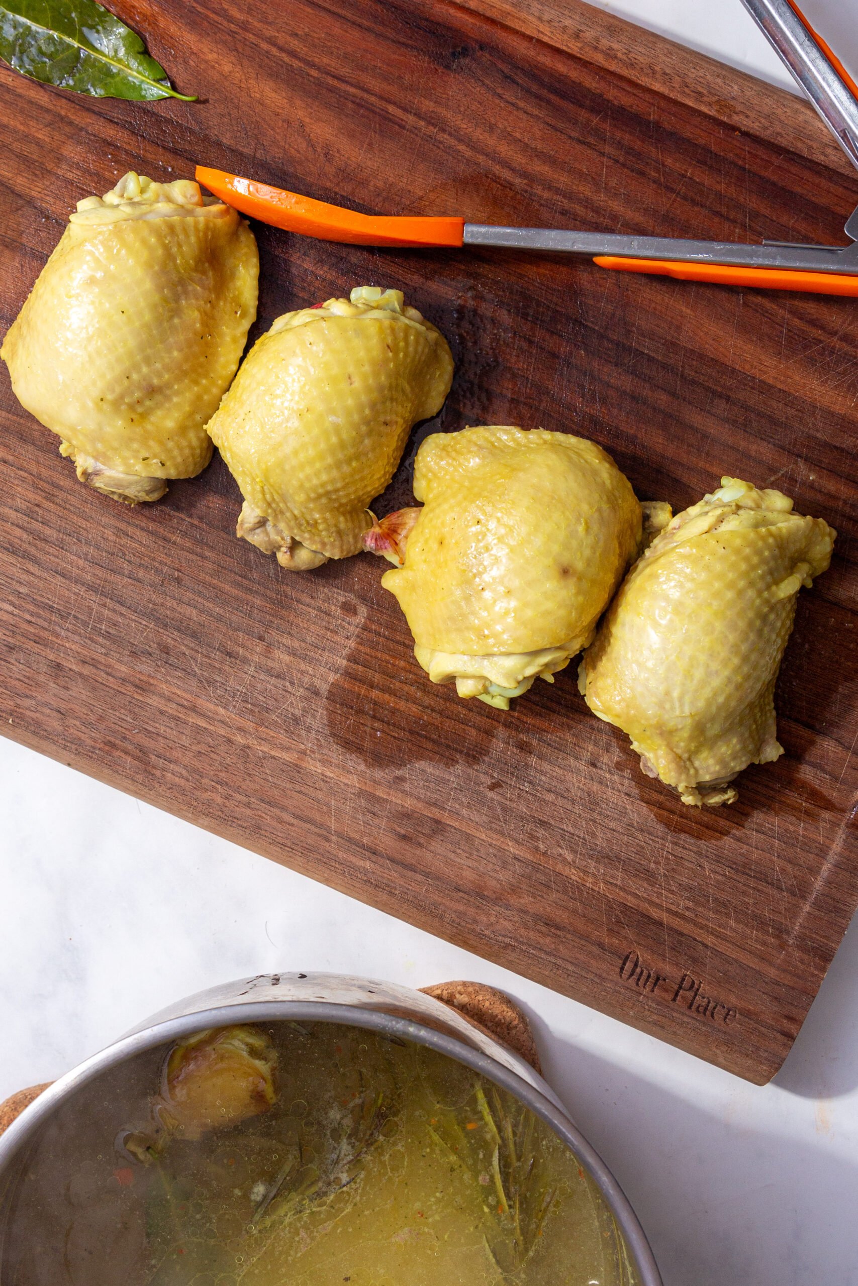 up close image of chicken thighs resting on a cutting board after being boiled