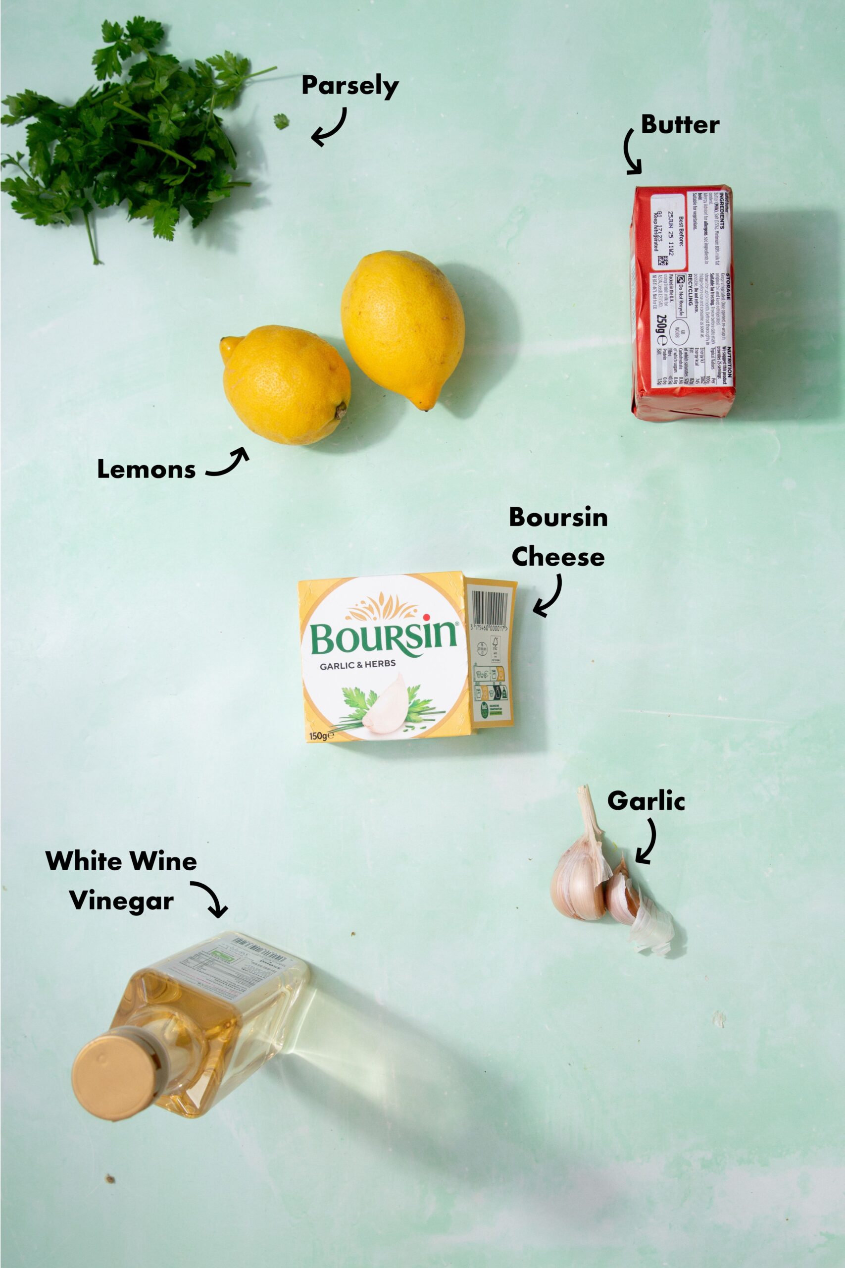 Ingredients to make the lemon cream sauce laid out on a pale blue background and labeled with arrows.