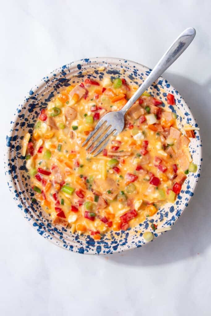 A colorful mixture of vegetables and eggs in a blue and white speckled bowl.