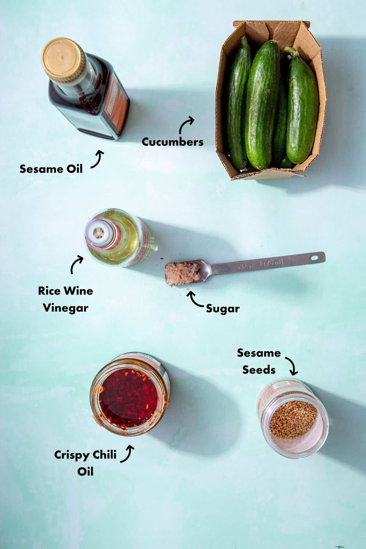 Ingredients to make the Din Tai Fung Cucumber Recipe laid out on a pale blue background and labeled with arrows.