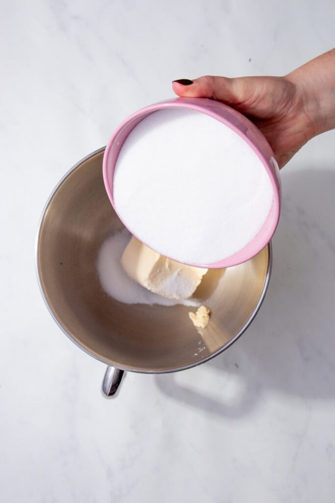 sugar being poured into bowl with butter. 