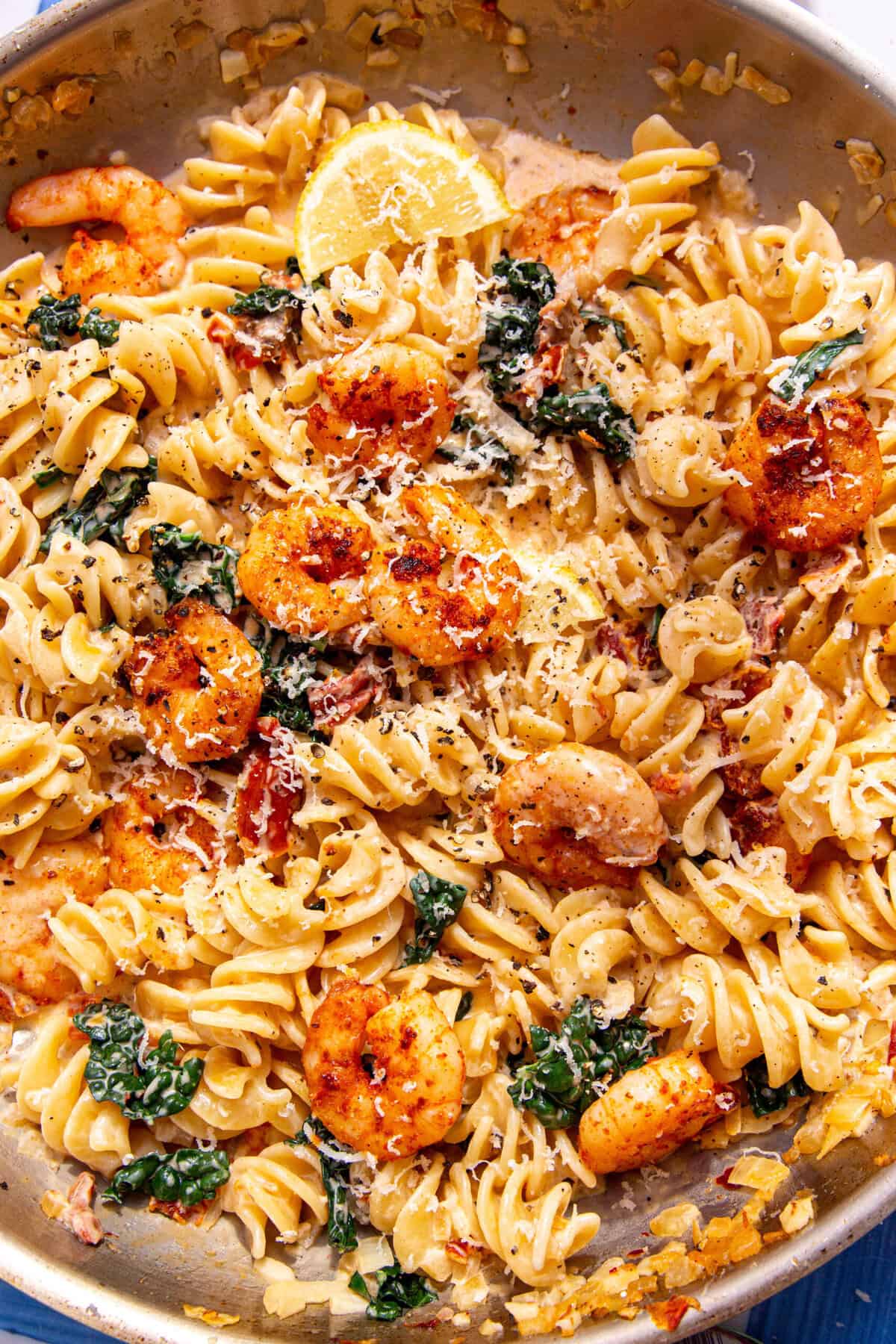 Creamy Shrimp Pasta with fusilli, juicy prawns, cavolo nero, parmesan cheese, and a fresh lemon wedge on top.