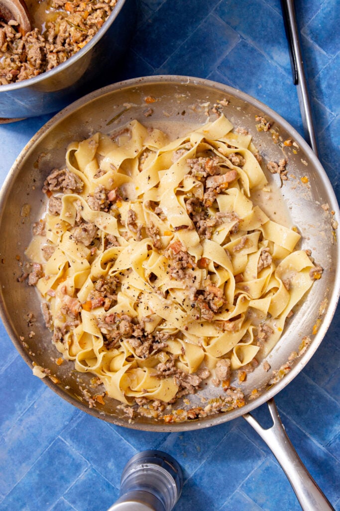 Pappardelle coated in creamy ragu bianco in a pan, ready to serve.