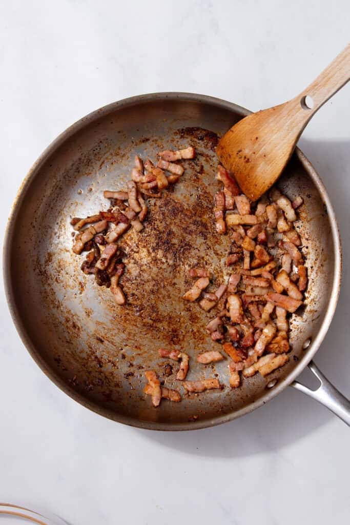 Crispy pancetta pieces in a pan.