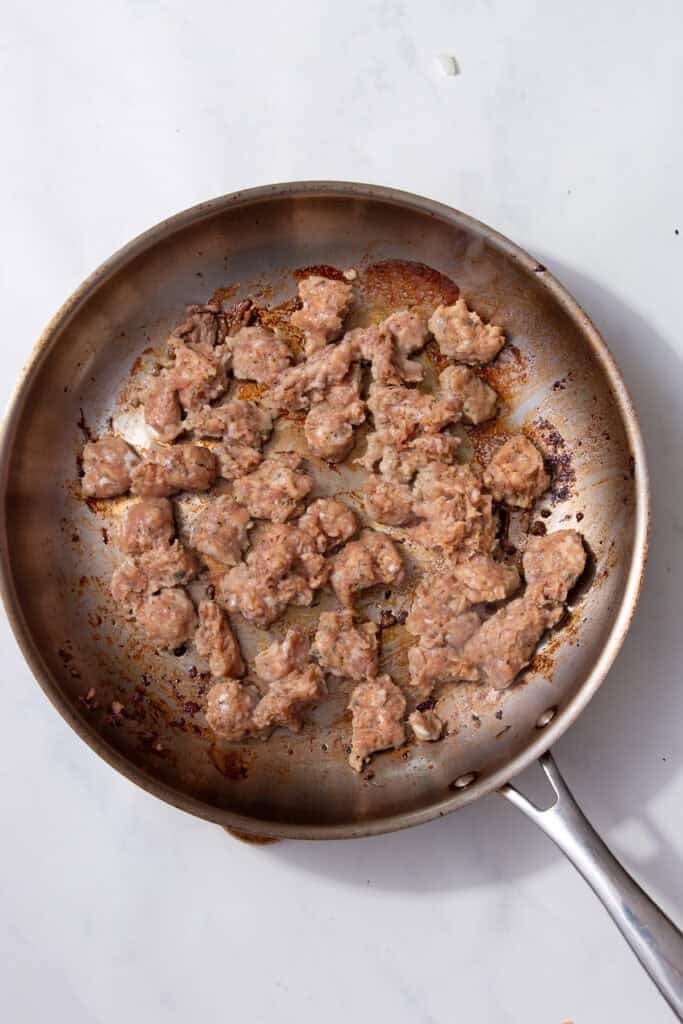 Sausage chunks browning in a hot pan.