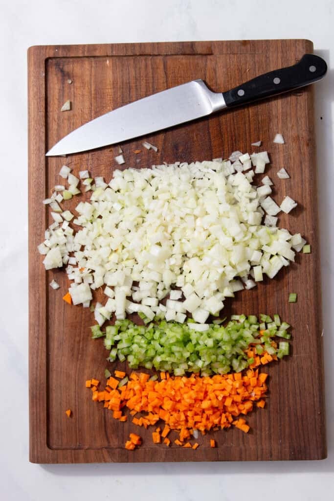 Finely diced onion, celery and carrot arranged on a wooden board for ragu bianco.