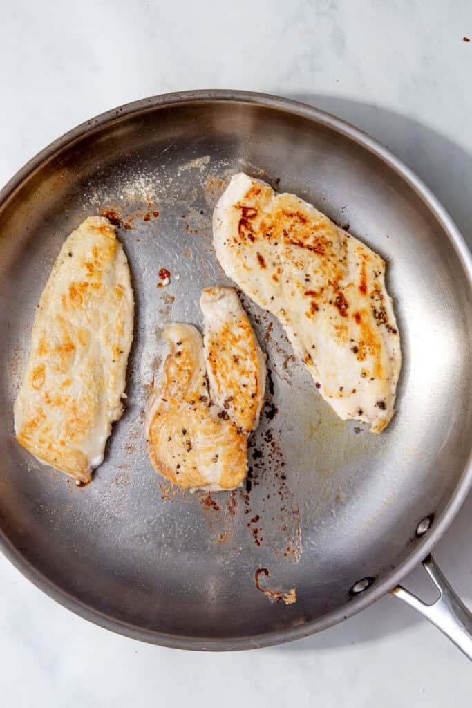 Chicken breasts seared to a light golden colour in the pan for chicken piccata.