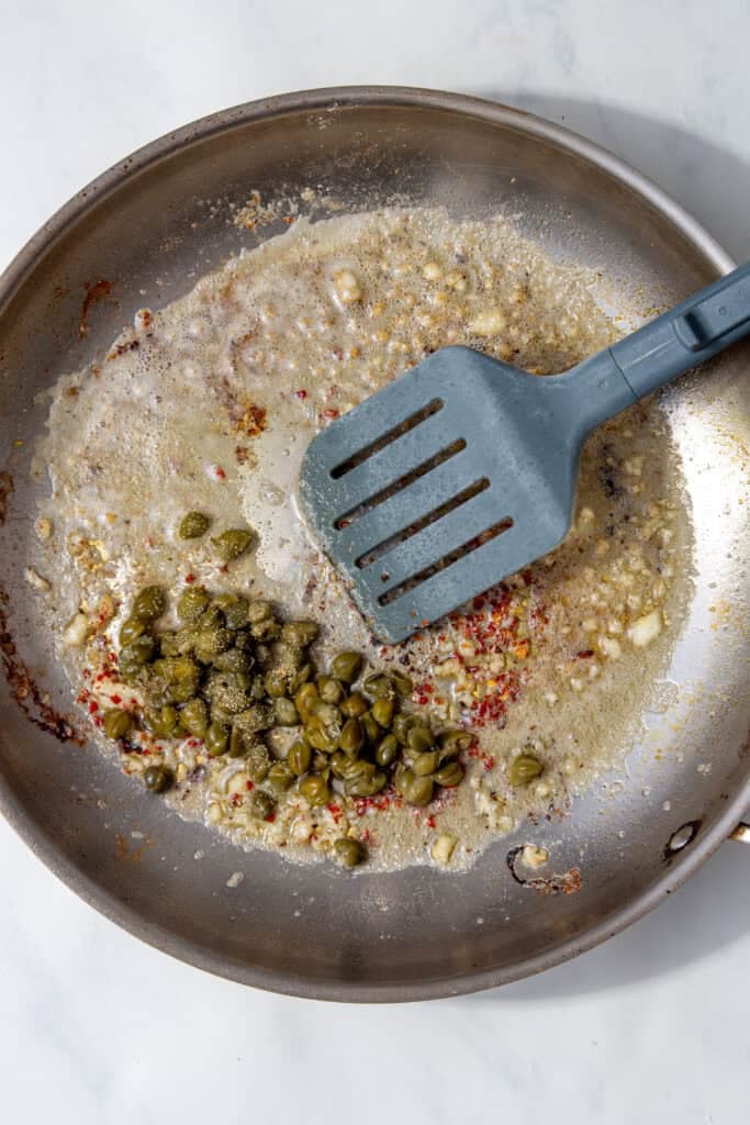 Capers and red pepper flakes stirred into the garlic butter with a spatula.