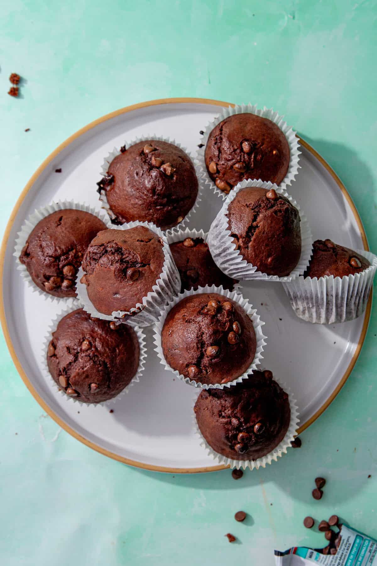 Freshly baked chocolate protein muffins with chocolate chips on a white plate, ready to serve.