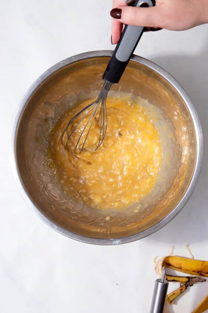 Whisking the banana mixture until smooth and creamy to form the muffin base.