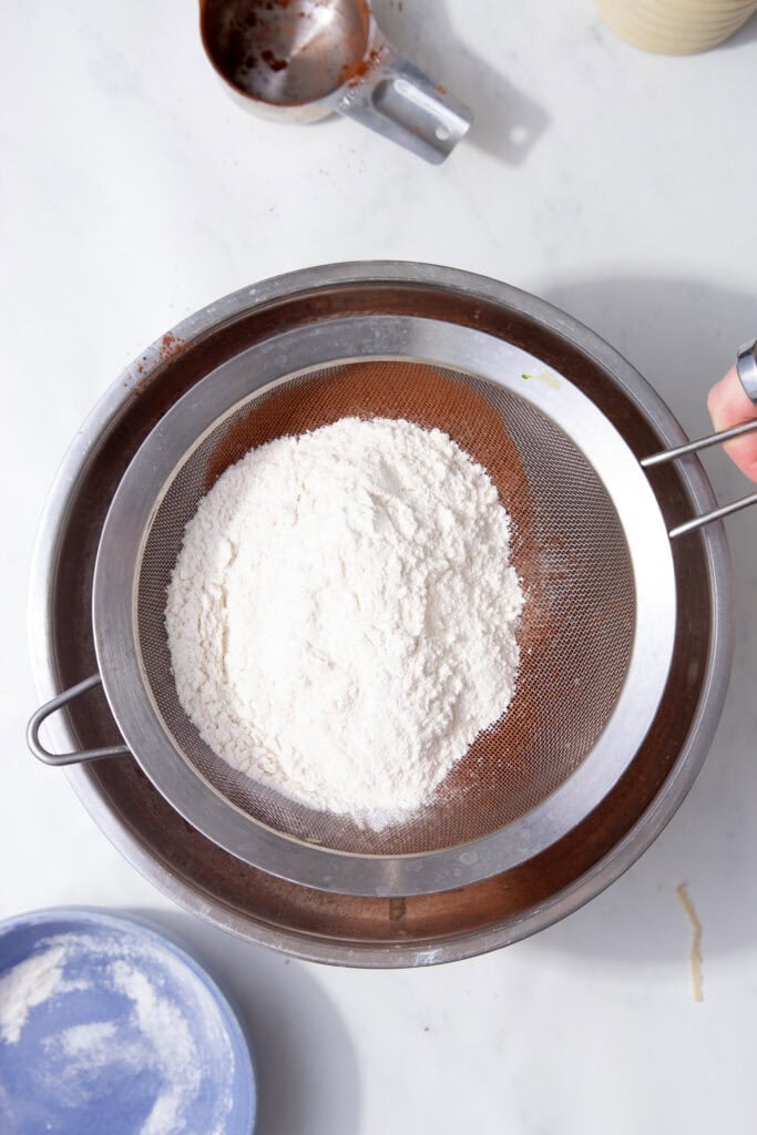Sifting plain flour over the wet muffin batter before adding cocoa and protein powder.