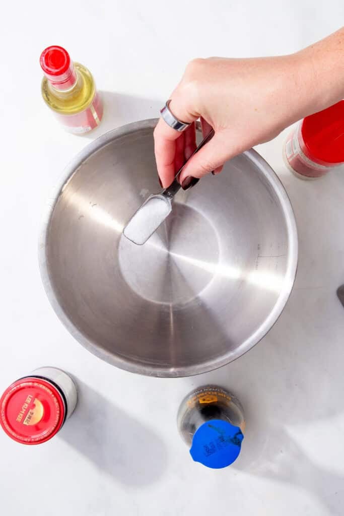 Adding sugar to a mixing bowl to start making easy gyoza dipping sauce.