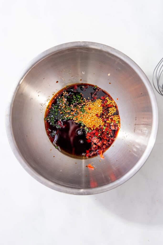 Soy sauce, rice vinegar, sesame oil, sesame seeds, chilli, and chives in a bowl for Japanese gyoza sauce.