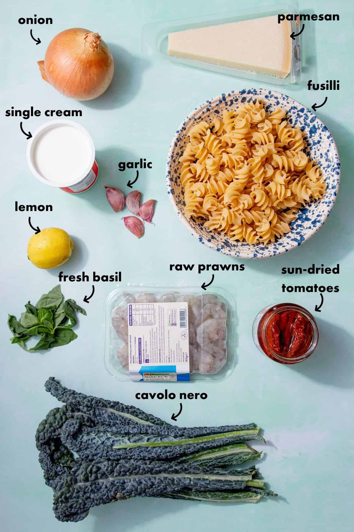 Ingredients for marry me shrimp pasta with fusilli, prawns, cavolo nero, sun-dried tomatoes, parmesan, and cream.