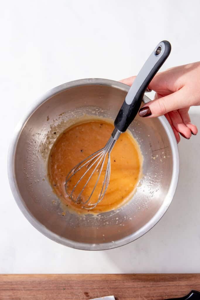 Smooth creamy miso dressing in a stainless steel bowl with a whisk.