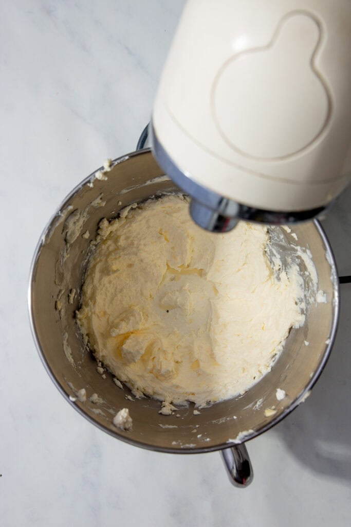 Butter being whipped in a stand mixer until pale and fluffy.