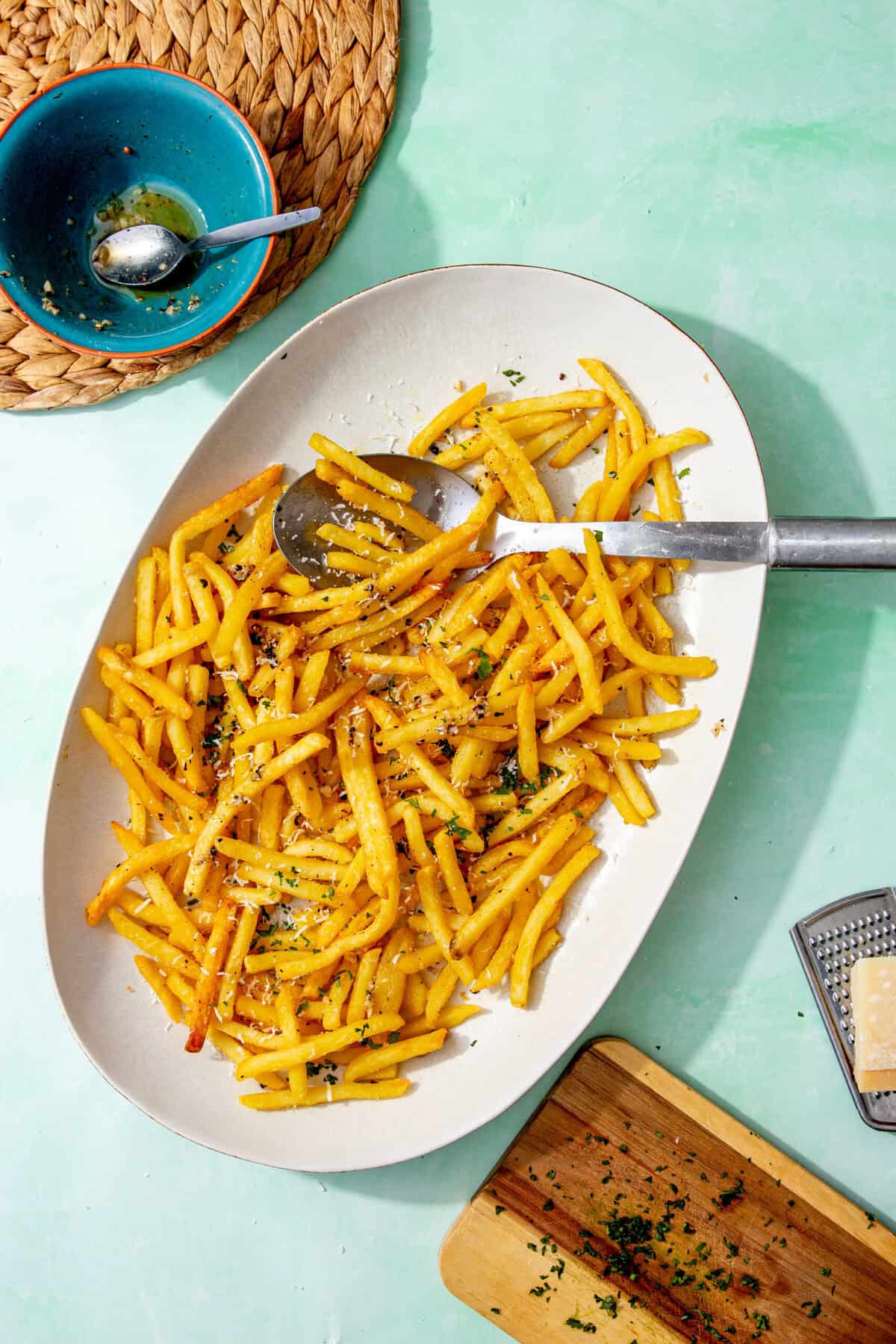 Golden garlic fries on a white platter, garnished with parsley and parmesan, ready to serve as a crispy, buttery side dish.