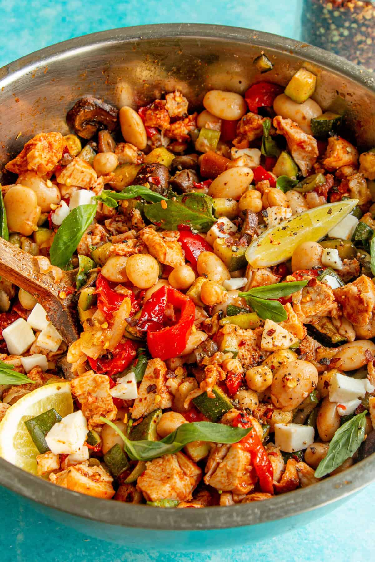 A bowl of dense bean salad with a spoon.