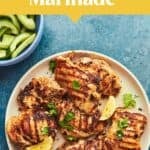 Grilled chicken thighs garnished with parsley and lemon wedges on a white plate, alongside bowls of sliced cucumbers and creamy sauce—plus text reading “Greek Yogurt Chicken Marinade”—make this dish perfect for any meal, just like a classic pork cutlet.