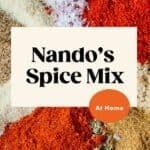 A close-up of various colorful spices, including red paprika, dried herbs, black pepper, and coarse salt—perfect for seasoning a pork cutlet—with text overlay: Nandos Spice Mix At Home on a cream and orange background.