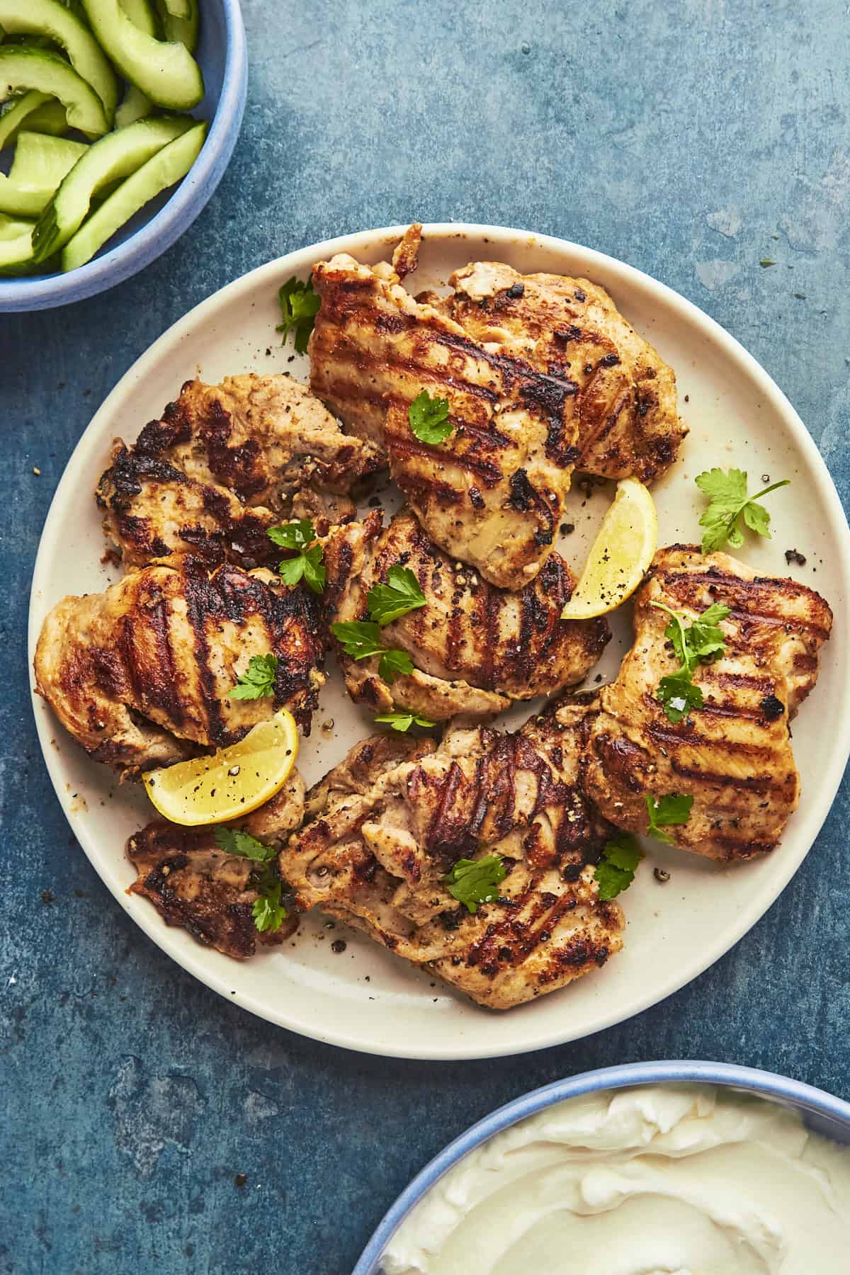 A plate of grilled meat, roasted corn, and lemon slices.