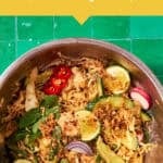 A bowl of Peanut Chicken Cabbage Salad with lime wedges, sliced radish, red onion, red chili, mint, and shredded chicken on a green tiled surface. Text above reads Perfect for Meal Prep.