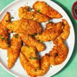 A plate of golden, crispy Shake and Bake Chicken tenders garnished with herbs sits on a green surface, with text reading Homemade Shake and Bake Chicken and Quick & Healthy Protein.