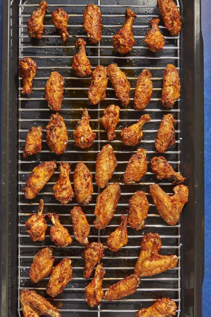 A tray of crispy, golden-brown chicken wings arranged in rows on a metal wire rack over a baking sheet—showcasing the perfect result when you follow the tips for how long to bake chicken wings at 400 for even cooking and delicious flavor.