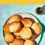 A plate of golden Vanilla Muffins on a teal surface, with a sliced muffin on a small blue-and-white plate and a jar of syrup nearby. Text reads: “Easiest Vanilla Muffin Recipe—Ready in 40 Minutes” and www.beatthebudget.com.