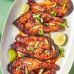 Oval platter with four Oven Baked Salmon Steaks garnished with sliced green onions and lime wedges, next to a bowl of lime pieces. Text reads: Oven Baked Salmon Steaks, In 20 Minutes!, and beatthebudget.com.