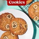 Four banana bread cookies with banana slices on top sit on a white plate and cooling rack. Text reads “Banana Bread Cookies” and “Bakery-style in 20 minutes.” Website URL: www.beatthebudget.com. Try these delicious banana bread cookies!.