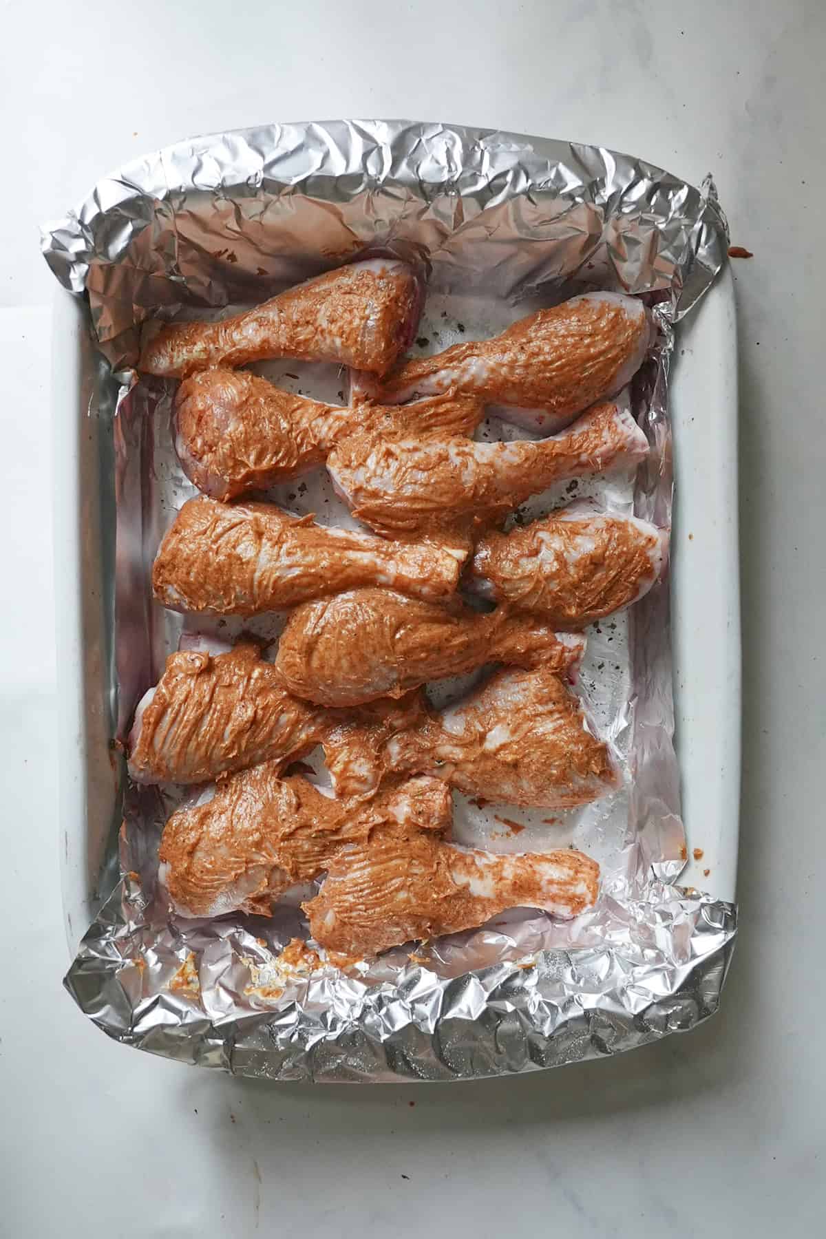 Basting the chicken drumsticks with the buttery pan juices at the halfway point