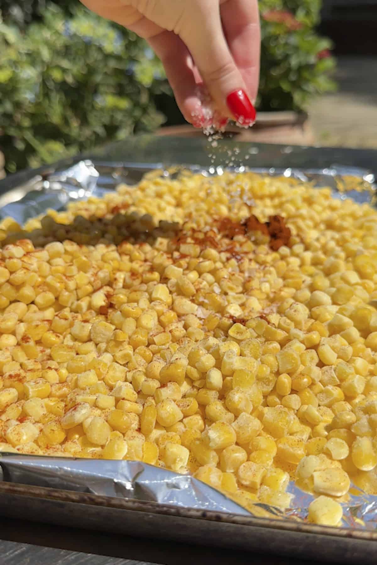 Frozen sweetcorn on a foil-lined baking tray seasoned with Cajun spices
