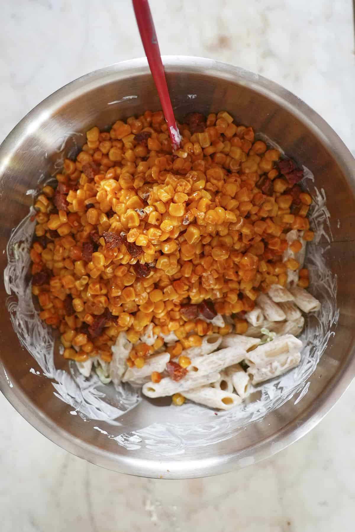 Penne pasta being rinsed under cold water after cooking
