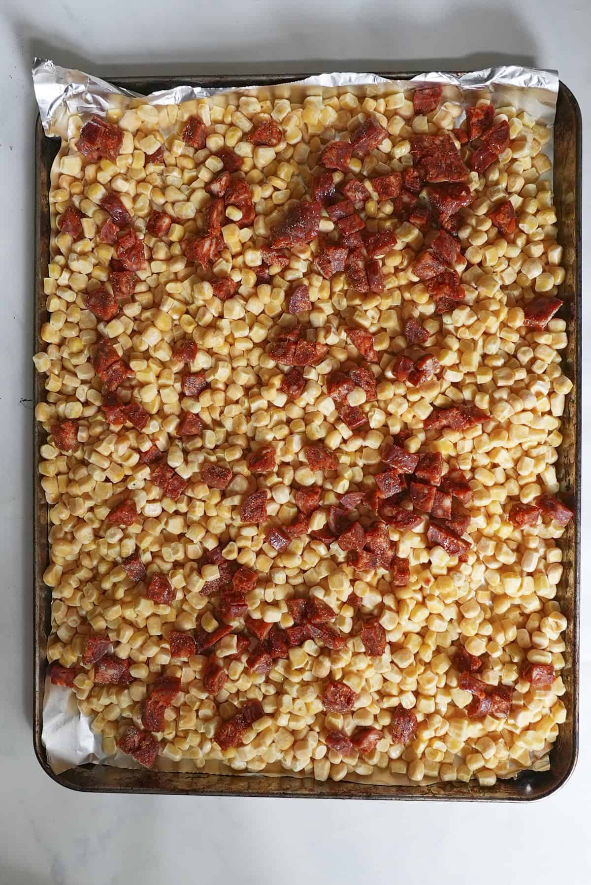 Chorizo and sweetcorn on a baking tray with olive oil and seasoning