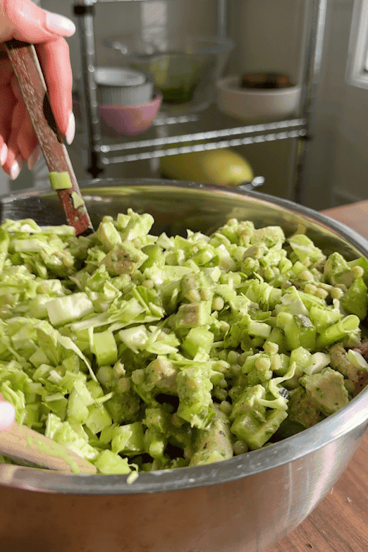 Green goddess dressing being poured over the salad and tossed to coat