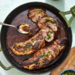 Sliced pork tenderloin in the oven on a board with pan sauce