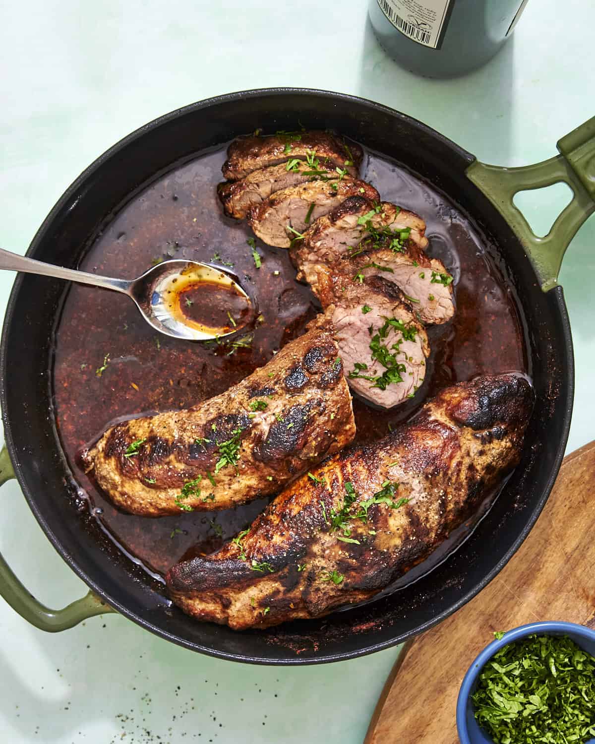 Sliced pork tenderloin in the oven on a board with pan sauce