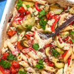 A baking dish filled with creamy baked feta pasta, zucchini, tomatoes, and fresh parsley. Text on the image reads: Viral Baked Feta Pasta and Low Effort Budget Dinner.