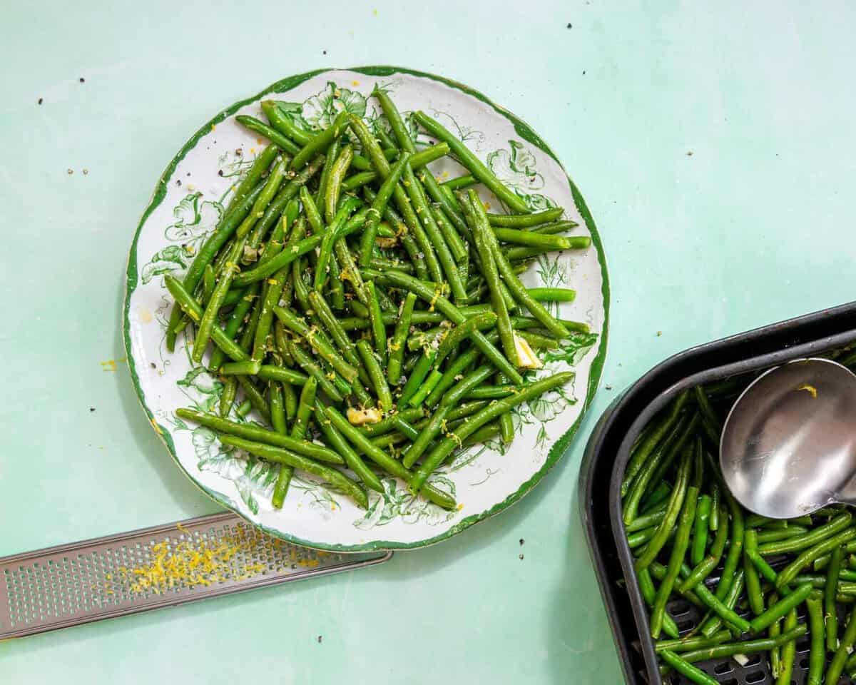 air fryer frozen green beans fully cooked on a white and green plate and a light blue background