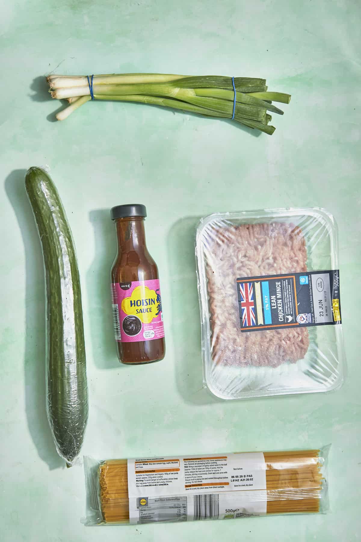 Ingredients for chicken hoisin noodles laid out flat including spaghetti, chicken mince and hoisin sauce