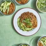 Chicken hoisin noodles divided into meal prep containers with curled spring onions