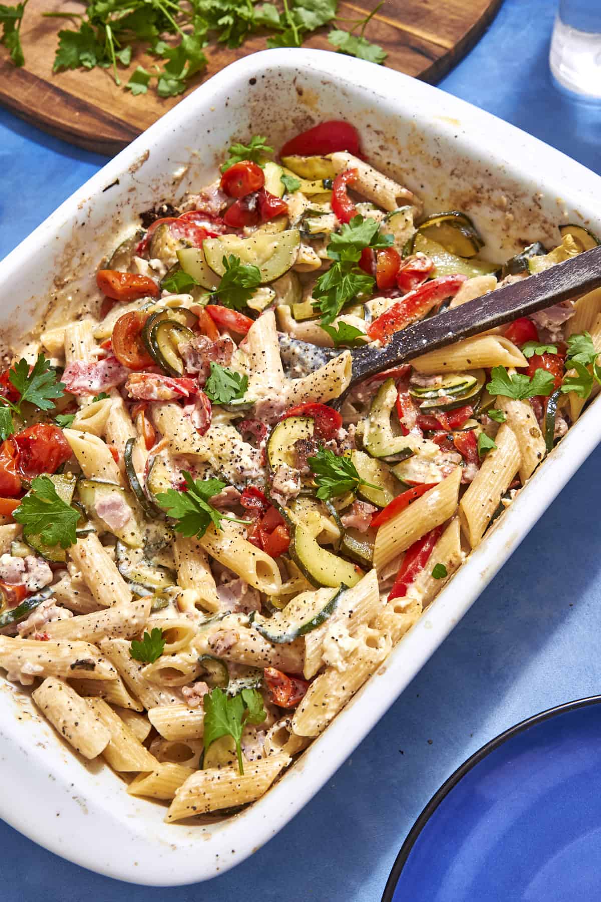 Baked feta pasta divided into meal prep containers topped with reserved bacon and veg