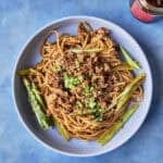 A bowl of budget dan dan noodles topped with crispy chicken mince, choi sum and spring onions.