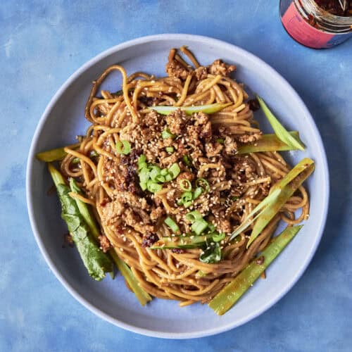 A bowl of budget dan dan noodles topped with crispy chicken mince, choi sum and spring onions.