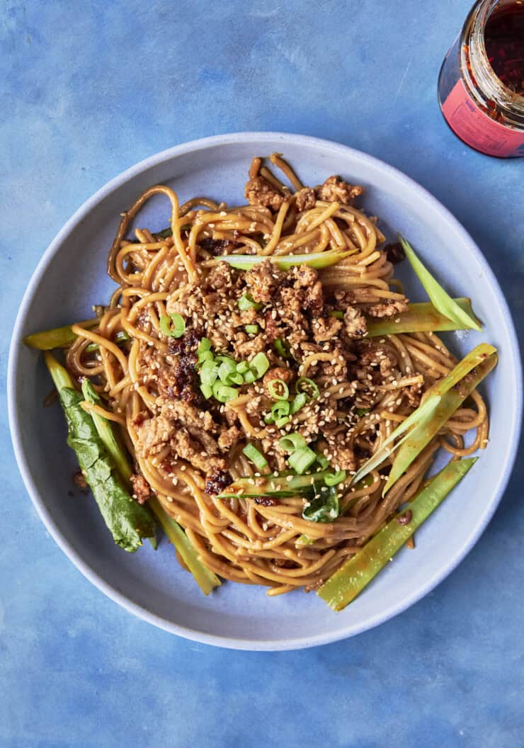 A bowl of budget dan dan noodles topped with crispy chicken mince, choi sum and spring onions.
