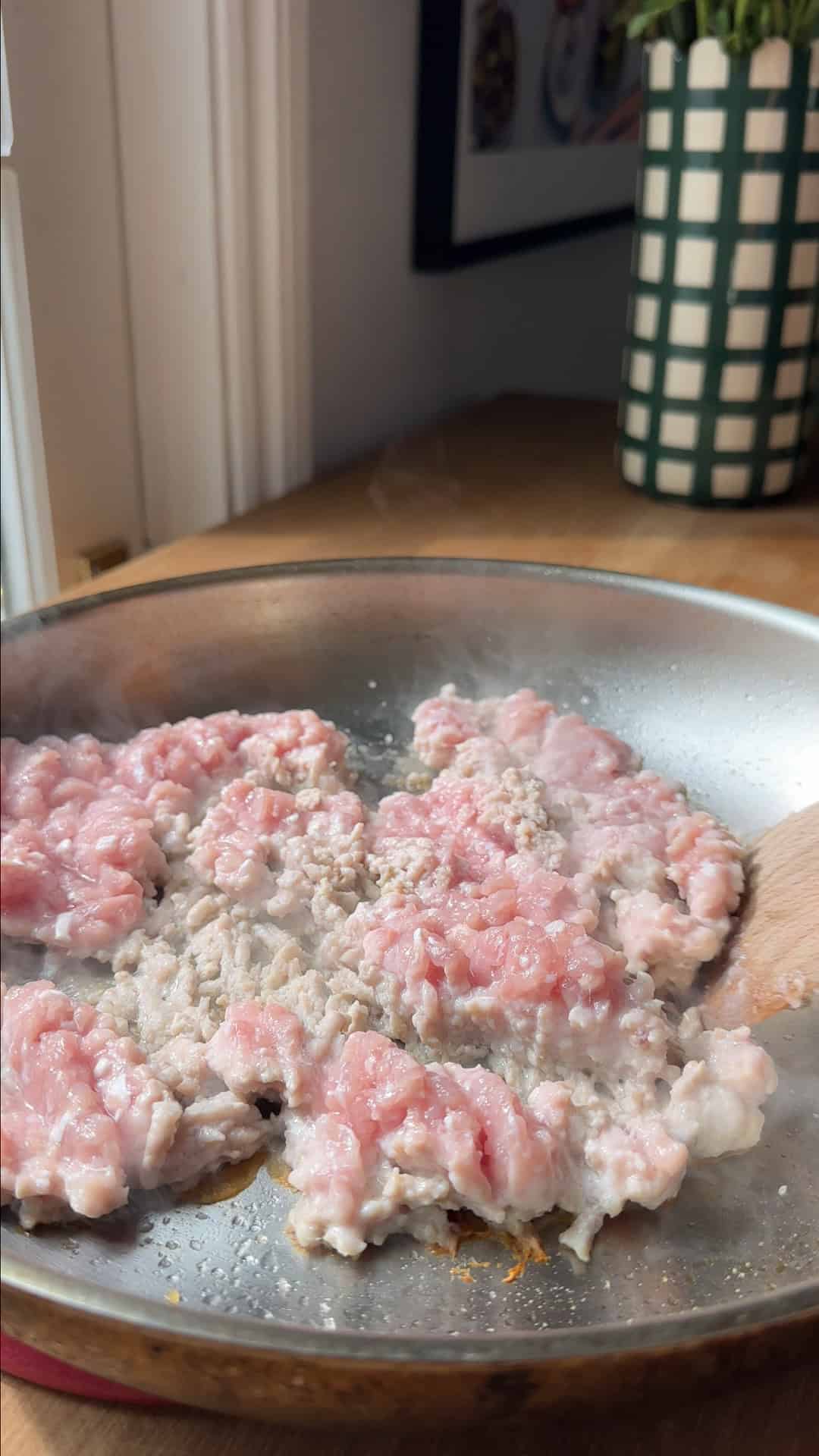 Chicken mince browning in a frying pan with sesame oil over high heat.