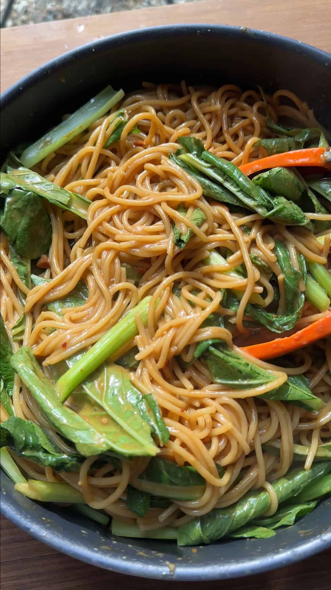 Finished dan dan noodle bowl topped with crispy chicken mince, choi sum, spring onions and chilli crisp.