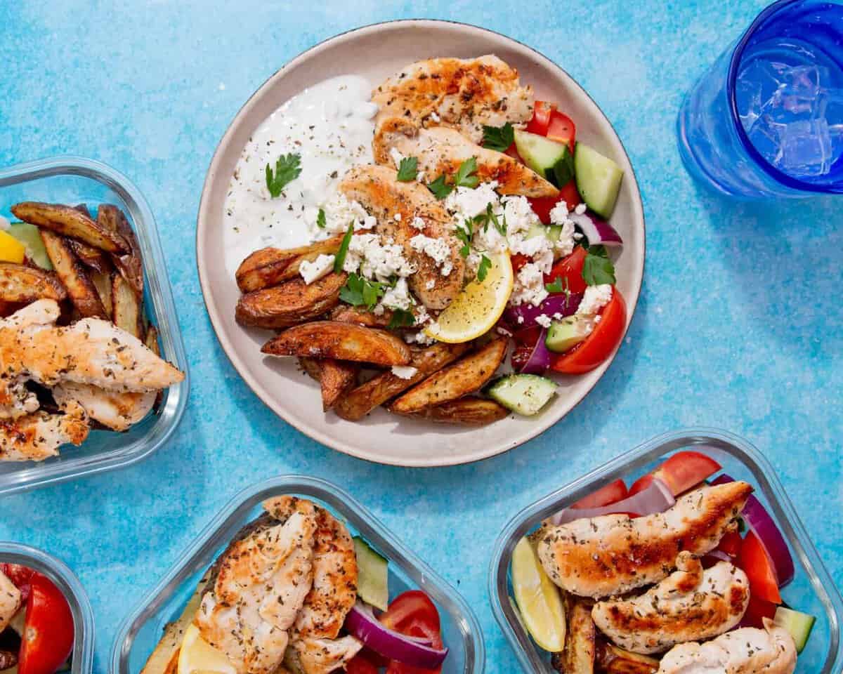 A bowl of salad with golden browned chicken pieces and potatoes in meal prep containers.
