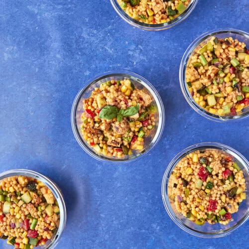 Nandos inspired giant couscous salad divided into meal prep containers with peri peri chicken